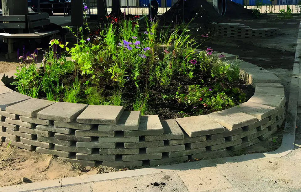 Ronde verhoogde plantenbak van stenen met bloeiende planten